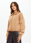 THE UPSIDE women's tan Carlotta Bomber Jacket is made from recycled fabric and made for a cropped fit. This fully insulated jacket features side seam pockets and metal arrow logo zipper.