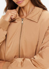 THE UPSIDE women's tan Carlotta Bomber Jacket is made from recycled fabric and made for a cropped fit. This fully insulated jacket features side seam pockets and metal arrow logo zipper.