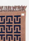 THE UPSIDE women's navy and tan cotton Ezra Beach Towel features a two-tone jacquard monogram design with knotted tassels at each end. Made for swim.
