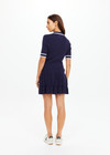 THE UPSIDE women's navy tennis Plume Knit Collared Dress fits true-to-size and features a drop waist with gathered skirt and a drawcord with tennis charms.