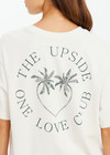 THE UPSIDE women's cream organic cotton Molokai Sammi Tee offers a oversized fit and features a green printed palm logo on front chest and back. Made for lifestyle.