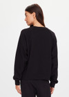 THE UPSIDE women's black organic cotton Lennox Raglan Crew Sweater offers a relaxed fit and features a classic crew neckline, ribbed. cuffs and hem. Finished with a subtle embroidered arrow logo at back. The perfect everyday sweater, made to last.