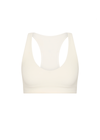 THE UPSIDE women's cream recycled soft peached Courtship Jetta Racerback Bra features a V neckline with removable cups and an elasticated underbust for support. Made for tennis, golf & pickleball.