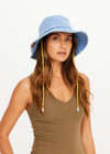 THE UPSIDE women's Washed Denim Bucket Hat features a wide brim silhouette, adjustable chin strap and topstitched detailing. Made for lifestyle.