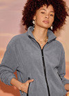 THE UPSIDE women’s grey recycled Sol Fleece Jacket has a relaxed fit with elastic waist and arm cuffs with polar fleece fabrication in marle. Made for lifestyle.