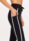THE UPSIDE women's black Sol 25inch Midi Legging offers a soft and supportive fit with a mid rise waist, side stripe detailing, pockets and adjustable drawcord. Made for yoga and pilates.
