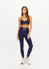 THE UPSIDE women’s navy recycled Eco Tech Salvador 25inch Midi Legging is mid rise and features side seam pockets, a cuffed hem and drawcord waist. Made for yoga and pilates.