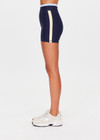 THE UPSIDE women's navy recycled nylon Hermosa 4 Inch Spin Short is mid rise and features a light blue stripe at upper waistband and pockets at the side. Made for yoga and pilates.