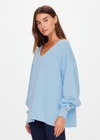 THE UPSIDE women's blue organic cotton Lou V Neck Sweater is an oversized fit and features dropped shoulders and a ribbed neckline and cuffs. Made for lifestyle.