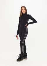 THE UPSIDE Banff Nova Jumpsuit in Black is a full length, long sleeve jumpsuit with contrast white piping at side seams, zipper detail, removable waist belt with buckle and thumb holes at cuffs.