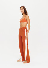 THE UPSIDE x THE BANYA orange rust Petra Flare is made from lenzing viscose fabrication and features splits at the front, contrast natural tape at side seams, elasticated waist and side seam pockets.