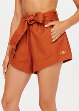 THE UPSIDE x THE BANYA orange rust short is made from heavy organic cotton and features a paper bag elastic waist, self-tie removable belt and welt pockets.