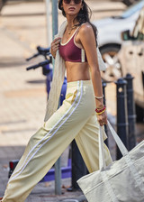 THE UPSIDE women's butter yellow Juliet Low Waist Trackpant is made from a slinky, lightweight fabric and feature side stripes, pockets and a split flared hem.