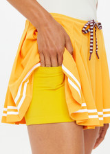THE UPSIDE women's mimosa yellow recycled fabric Prix Quinny Pleated Skirt features a inner spin short with pockets and elasticated drawcord waist. Made for tennis.