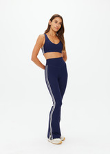 THE UPSIDE women's navy recycled peached Florence Flare Pant is a high-rise pant in a breathable fabric, featuring cream side stripes. Perfect for pilates.