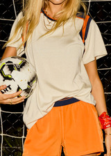 THE UPSIDE women’s cream cotton Elixir Seven Tee is designed for a relaxed fit and features orange and navy stripes on neckline and shoulders. Made for everyday wear.