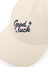 THE UPSIDE women’s cream Good Luck Soft Cap features an embroidered 'Good Luck' on front with an adjustable strap at the back.