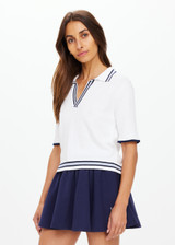 THE UPSIDE women's white tennis, pickleball & padel Archie Collared Knit Polo is made from organic cotton and features navy & dusty blue striped ribbing at front placket, collar and hem.