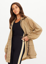 THE UPSIDE women's brown Rylan Anorak is relaxed fit, mid-length, made from tan wrinkled water-resistant fabric. Made for yoga & pilates.
