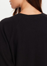 THE UPSIDE women's black organic cotton Lennox Raglan Crew Sweater offers a relaxed fit and features a classic crew neckline, ribbed. cuffs and hem. Finished with a subtle embroidered arrow logo at back. The perfect everyday sweater, made to last.