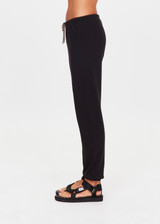 THE UPSIDE women's black organic cotton Kayne Track Pant is a classic mid-rise track pant and features a soft elasticated waistband with a brown paracord drawcord, elasticated cuffs and finished with a subtle embroidered arrow logo at back. The perfect everyday track pant, made to last.