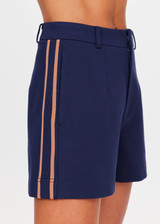 THE UPSIDE women's navy Toledo Leon Bermuda Short is a longline tailored short featuring tan knitted tape down sides, flat waistband with belt loops and side pockets. Made for lifestyle.