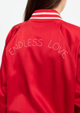 THE UPSIDE women's red 100% silk Two Hearts Silk Bomber Jacket is fully lined with cream and red stripes, welt pockets with triangle detail at top and bottom and an embroidered horse and horseshoe design. Made for lifestyle.