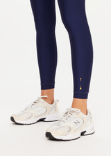 THE UPSIDE women’s navy recycled Eco Tech Salvador 25inch Midi Legging is mid rise and features side seam pockets, a cuffed hem and drawcord waist. Made for yoga and pilates.