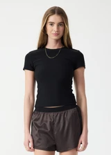 THE UPSIDE women's black Divina Isabella Baby Tee is designed for a soft and supportive fit in cotton modal fabrication and features a printed logo arrow in cream. Made for lifestyle.