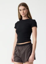 THE UPSIDE women's black Divina Isabella Baby Tee is designed for a soft and supportive fit in cotton modal fabrication and features a printed logo arrow in cream. Made for lifestyle.