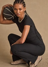 THE UPSIDE women's black Divina Isabella Baby Tee is designed for a soft and supportive fit in cotton modal fabrication and features a printed logo arrow in cream. Made for lifestyle.