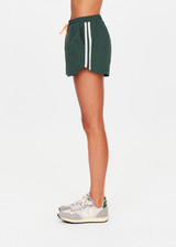 THE UPSIDE women’s green Billie Run Short is a mid-rise style featuring cream mesh binding down the sides and an orange drawcord. Made for high impact.