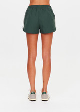 THE UPSIDE women’s green Billie Run Short is a mid-rise style featuring cream mesh binding down the sides and an orange drawcord. Made for high impact.