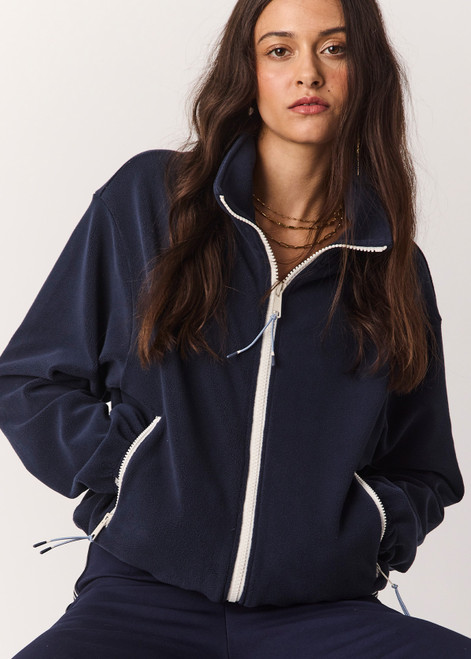 THE UPSIDE women’s navy recyled Sol Fleece Jacket offers a relaxed fit and features a zip through front, front zip pockets, elasticated waist and cuffs and contrast paracord zip pullers. Made for lifestyle.