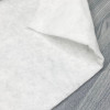 White polyester quilt batting folded on a gray wood surface