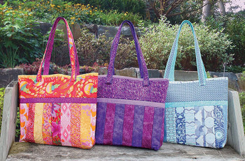 Three colorful finished Sophie Quilt As You Go tote bags outdoors