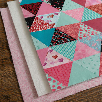 King-size cotton poly batting layered beneath a pink and aqua patchwork quilt