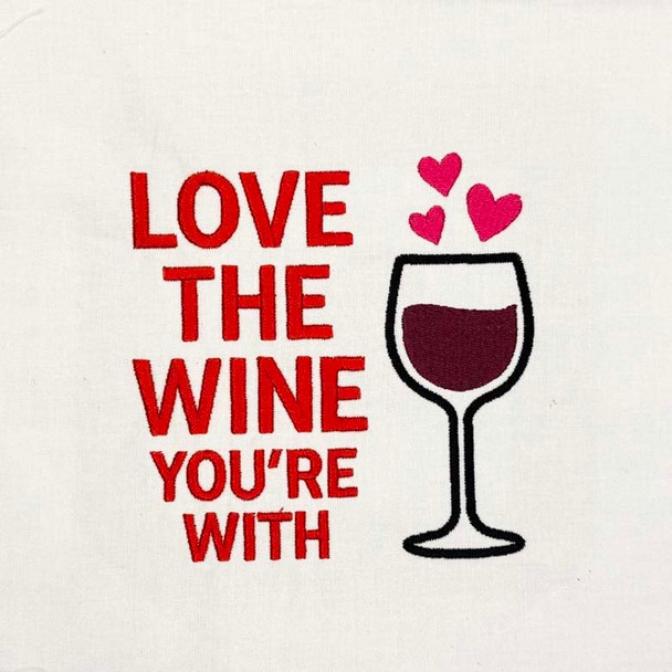 Love the Wine You’re With machine embroidery design with wine glass and hearts stitched in red and burgundy on white fabric