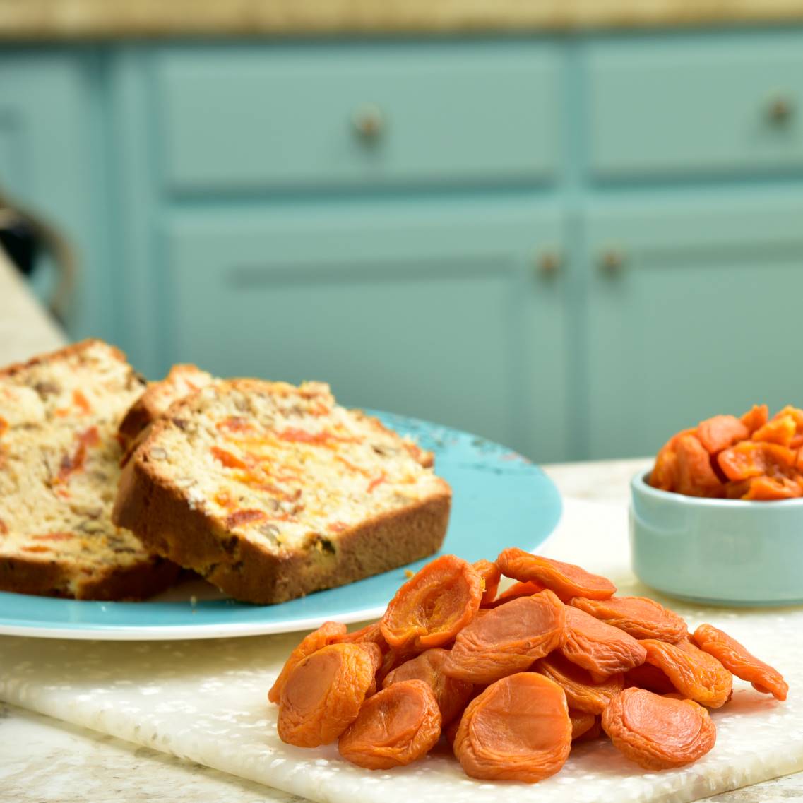 Dried apricots with a plate of apricot bread in the background