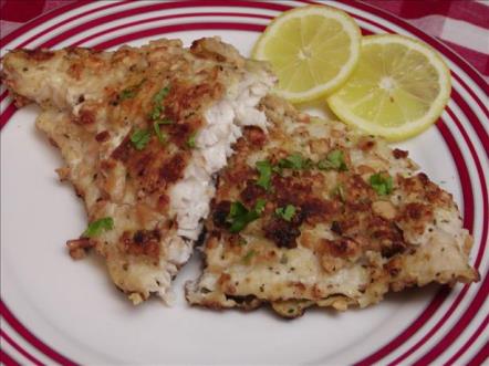Filet of Cashew Catfish on a dinner plate with two slices of lemon