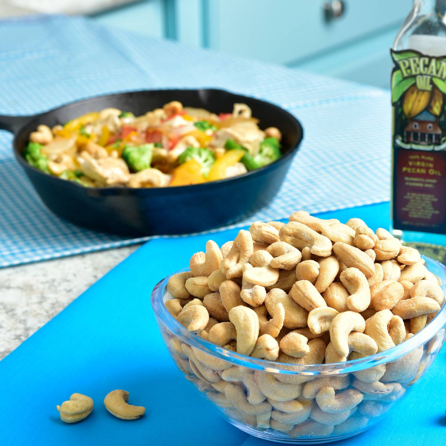 A bowl of cashews with the one skillet cashew chicken stir fry in the background