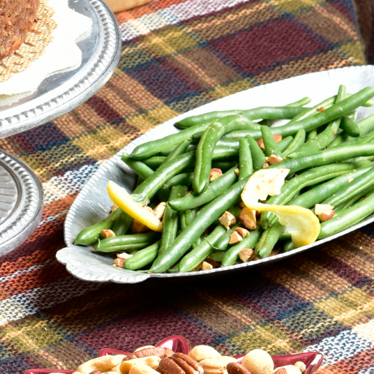 Garlic Roasted Green Beans with Almonds on a serving dish on a plaid tableclothj