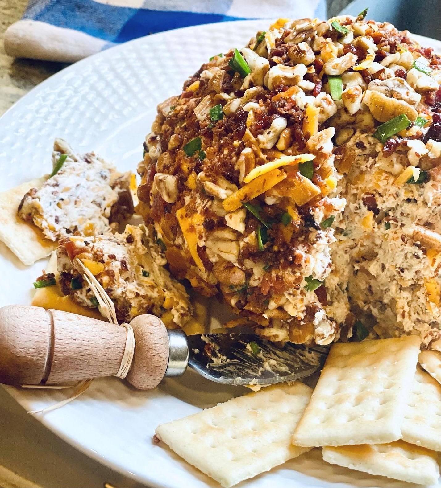 Bacon Pecan Cheeseball on a platter with a serving knife and crackers