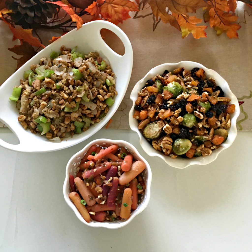 Three bowls with Holiday Carrot Salad, Roasted Brussels Sprouts, Cinnamon Butternut Squash, Pecans, and Raisins, and Low- carb pecan stuffing