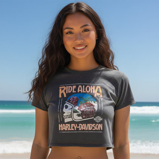 Front view of a woman on a tropical beach wearing the grey heather Harley-Davidson Women's Protea Cropped Tee with the Ride Aloha graphic