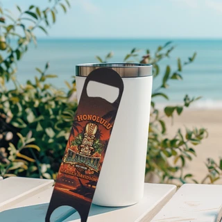 Honolulu Harley-Davidson Tiki Guy Bottle Opener leaning against a white tumbler on a table outdoors