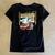 Back view of woman wearing black Harley-Davidson Tiki Tropical V-Neck Tee on Hawaiian beach