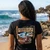 Back view of woman wearing black Harley-Davidson Tiki Tropical V-Neck Tee on Hawaiian beach