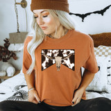 Cowhide Bullhead DTF Heat Transfer, a graphic design of a cow skull with bull horns on a brown T-shirt worn by a woman.