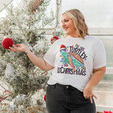 I'm Like Turtley Into Christmas DTF Heat Transfer, woman wearing a Christmas-themed t-shirt featuring a colorful turtle wearing a Santa hat, holiday decorations, Christmas tree, and festive ornaments.